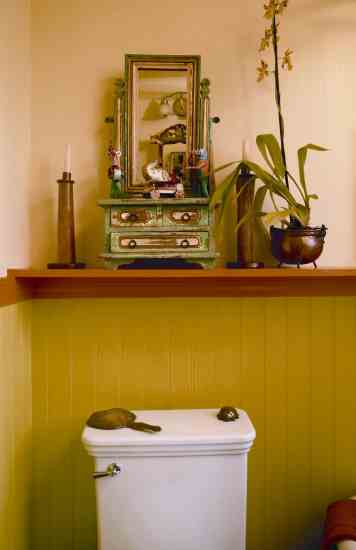 The vignette along a painted ledge in the main floor bathroom is of an antique painted vanity and a three-footed copper pot with an orchid.